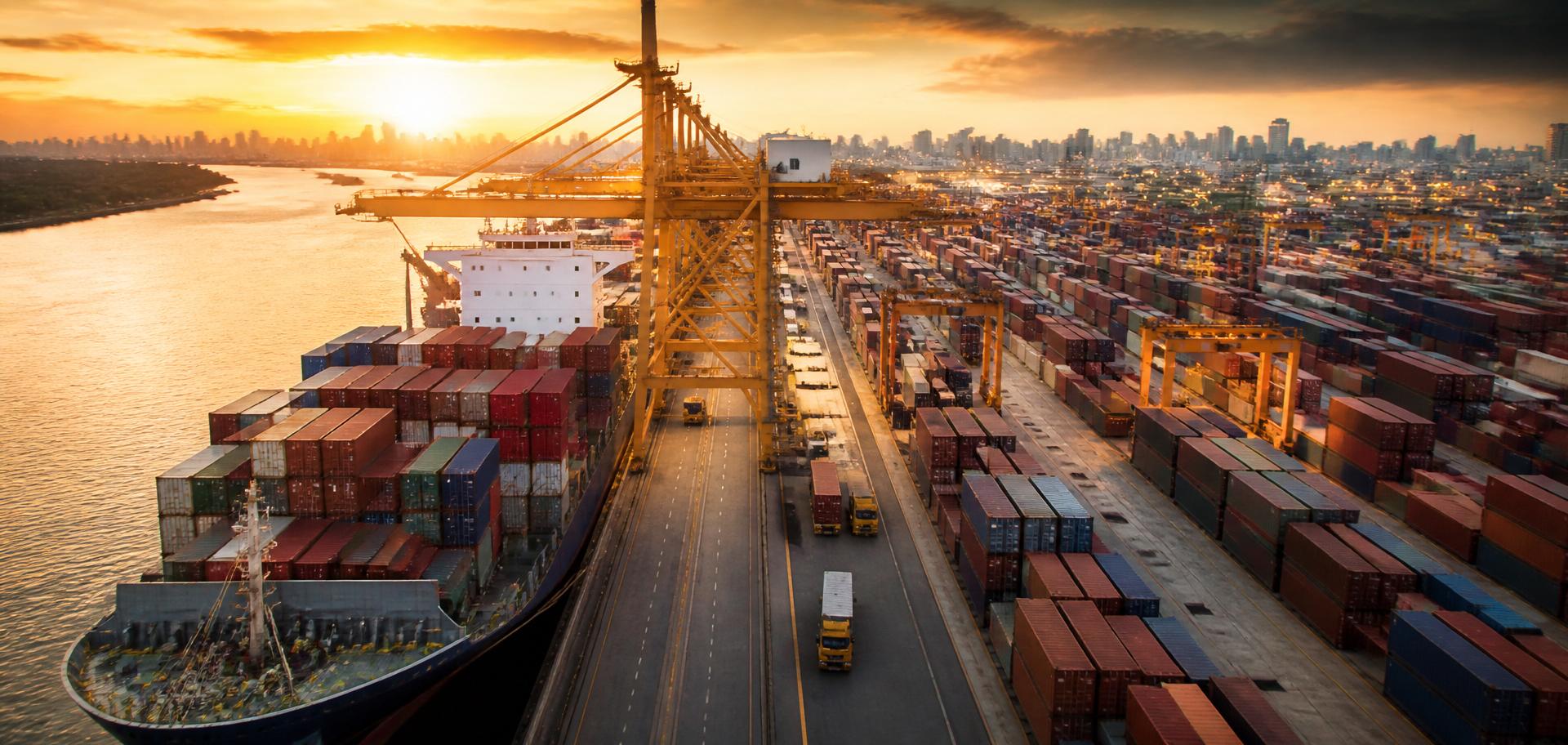 Buque de carga cargado con contenedores en un puerto internacional ocupado al atardecer